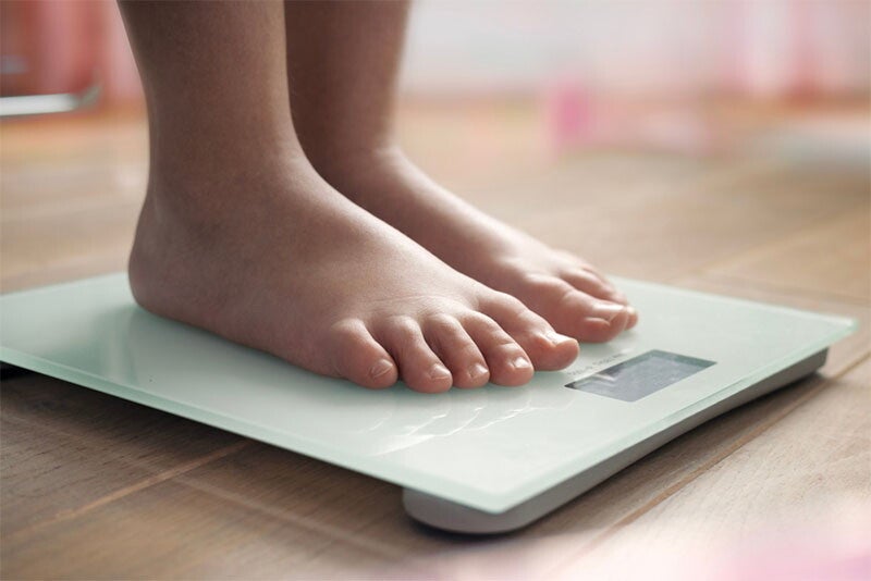 Child's feet stand on a weighing scale during a pediatrician checkup