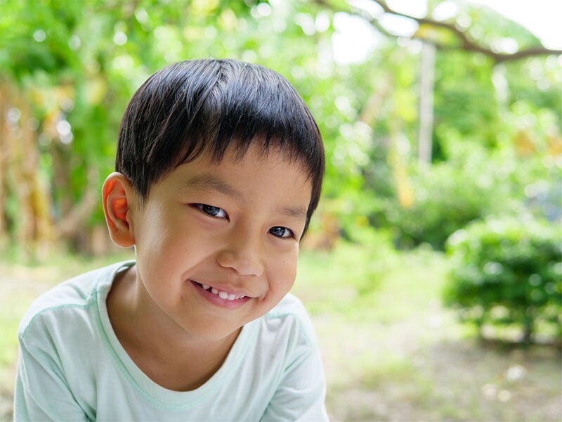 Filipino male preschooler flashes a big smile while outdoors