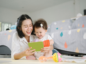 Asian mom and toddler daughter happily reading Asian mom and toddler daughter happily reading