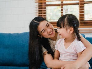 Asian woman sits her child on her lap and looks at her lovingly after she had to discipline her Asian woman sits her child on her lap and looks at her lovingly after she had to discipline her