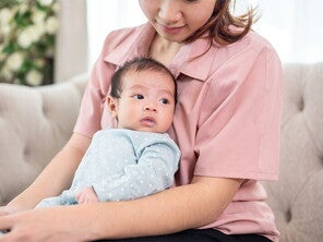 Mom holding newborn baby on couch Mom holding newborn baby on couch