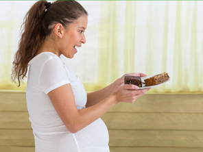 Pregnant woman holding plate with two pieces of cake Pregnant woman holding plate with two pieces of cake