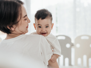Smiling Asian mom with her laughing baby enjoys the early childhood stage Smiling Asian mom with her laughing baby enjoys the early childhood stage