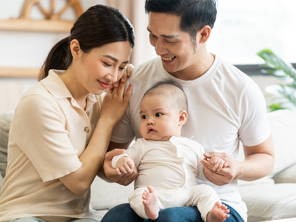 Smiling mother and father holding newborn son at home, considering birth control methods for family planning Smiling mother and father holding newborn son at home, considering birth control methods for family planning