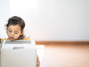 A photo of a little girl breathing in clean air from an air purifier at home A photo of a little girl breathing in clean air from an air purifier at home