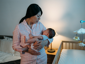 A sleepy Asian mom in pajamas carrying her newborn, who’s fussy because of colic in babies A sleepy Asian mom in pajamas carrying her newborn, who’s fussy because of colic in babies