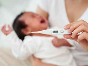 An Asian mom checks her her baby for fever using a thermometer An Asian mom checks her her baby for fever using a thermometer