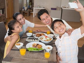 Asian boy takes a selfie with his family before they eat a meal that includes minerals in food.