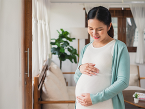 Asian woman at 27 weeks pregnant holds her baby bump Asian woman at 27 weeks pregnant holds her baby bump