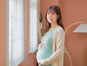 Asian woman, who is 39 weeks pregnant, holds her belly bump and smiles at the camera. Asian woman, who is 39 weeks pregnant, holds her belly bump and smiles at the camera.