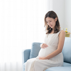 A 29 weeks pregnant Asian woman lovingly holding and looking at her belly at home A 29 weeks pregnant Asian woman lovingly holding and looking at her belly at home