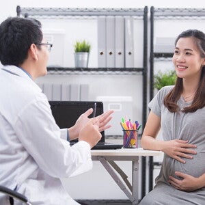A pregnant Asian woman talking to her doctor, learning about the 4 stages of labor