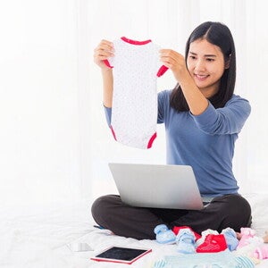A young 8 weeks pregnant Asian woman shopping online for her baby