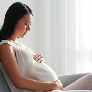 A young woman holding her belly while seated at 16 weeks pregnant. A young woman holding her belly while seated at 16 weeks pregnant.
