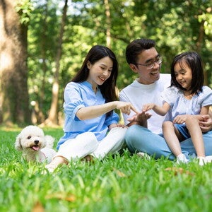 Asian couple with their dog play with their daughter outdoors