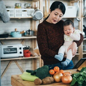 Asian mom and son looking at table of vegetables