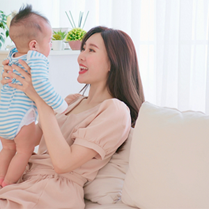 Asian mother holds and talks to her baby on the sofa at home, feeling healthy with proper postpartum care. Asian mother holds and talks to her baby on the sofa at home, feeling healthy with proper postpartum care.