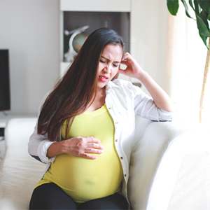 Asian pregnant woman winces in pain due to heartburn Asian pregnant woman winces in pain due to heartburn