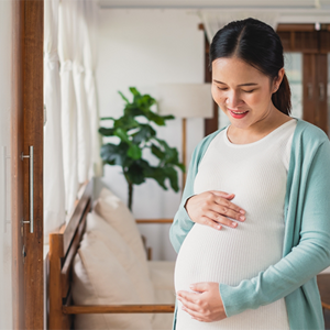 Asian woman at 27 weeks pregnant holds her baby bump Asian woman at 27 weeks pregnant holds her baby bump