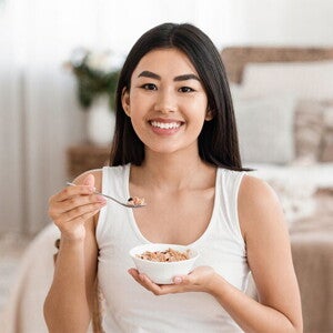 Asian woman eats a bowl of oatmeal