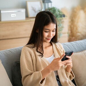 Asian woman looking at her phone's calendar to check her ovulation days. 