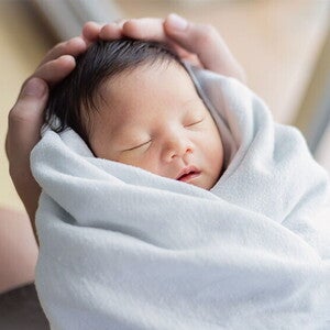 Closeup of healthy newborn in a swaddle being held by the father