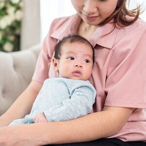 Mom holding newborn baby on couch