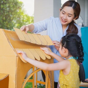 Mom and daughter making a cardboard house. 