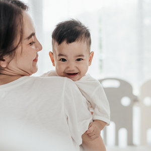 Smiling Asian mom with her laughing baby enjoys the early childhood stage Smiling Asian mom with her laughing baby enjoys the early childhood stage