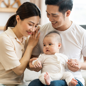 Smiling mother and father holding newborn son at home, considering birth control methods for family planning
