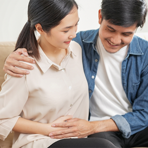Young Asian 6 weeks pregnant woman with her husband holding her belly on the sofa Young Asian 6 weeks pregnant woman with her husband holding her belly on the sofa