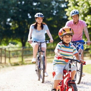 Young Asian family of three go biking at a park to prevent child obesity.