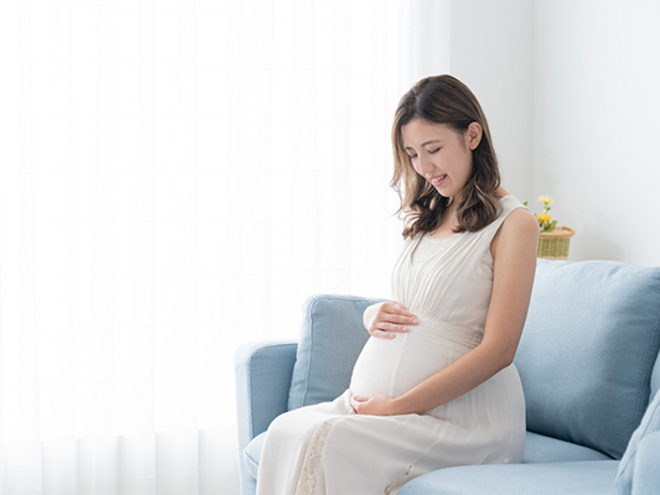 A 29 weeks pregnant Asian woman lovingly holding and looking at her belly at home A 29 weeks pregnant Asian woman lovingly holding and looking at her belly at home
