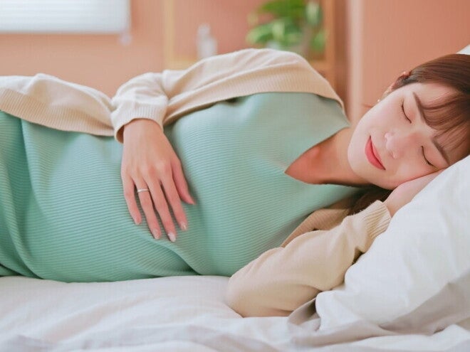 Header_Image Young Asian mom at Week 20 of pregnancy sound asleep in bed.